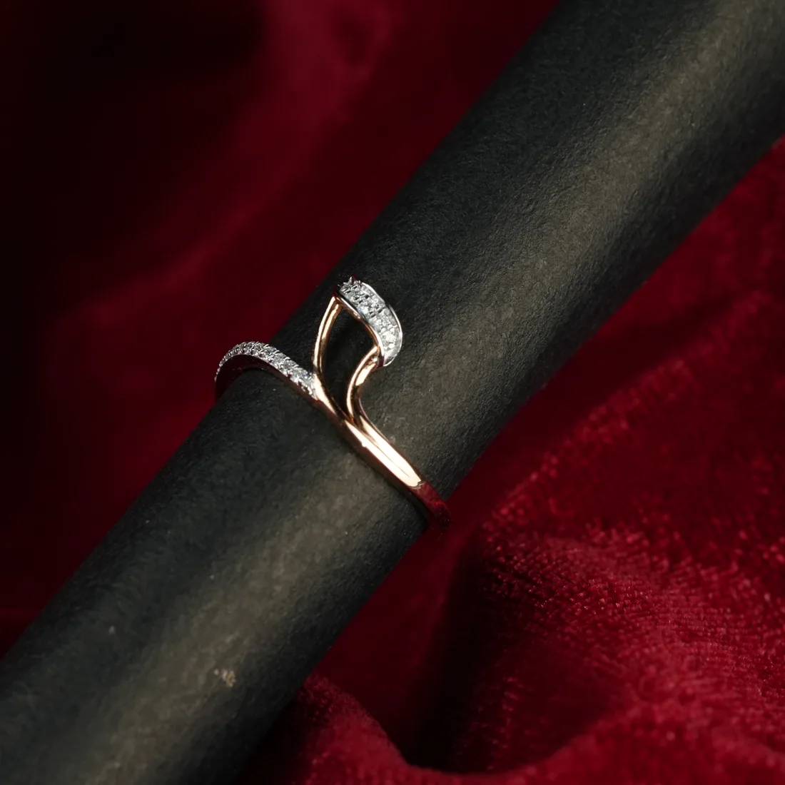 A finished diamond ring on a polishing rod against red velvet.