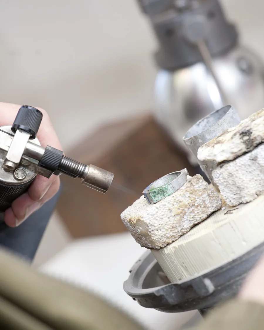 A torch flame playing over a piece on a soldering block.