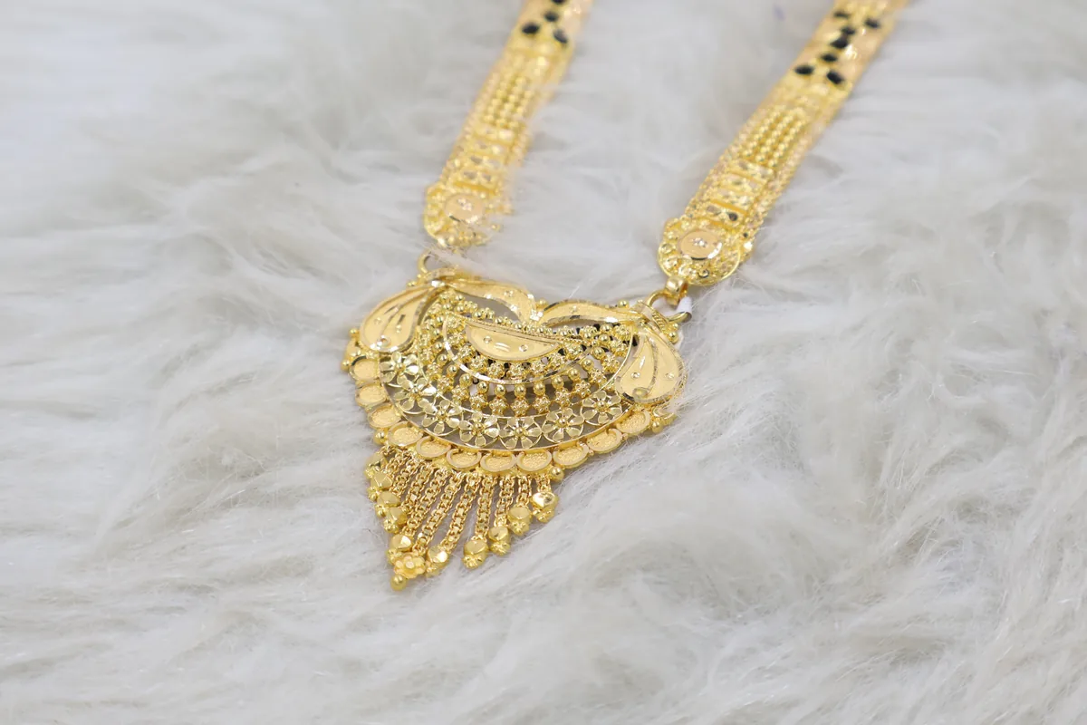 A gold haram laid out flat, lit softly.