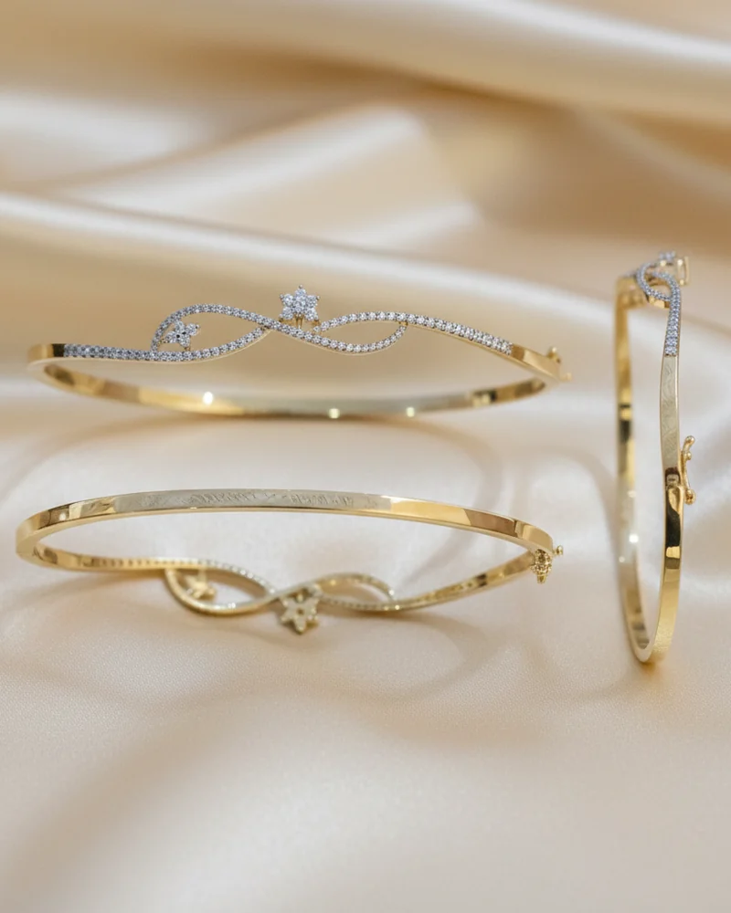 An open gold bracelet whose two ends cross with diamonds at the tips.