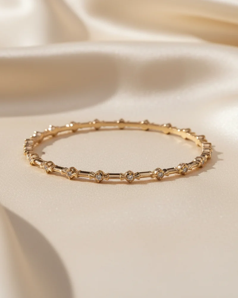 A narrow gold bangle built from fine links set with small diamonds.