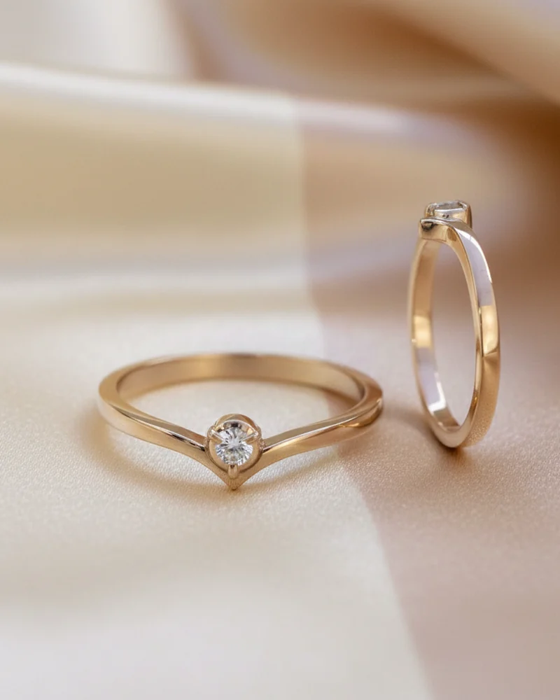 A slim gold ring whose band crosses over beneath a single diamond.