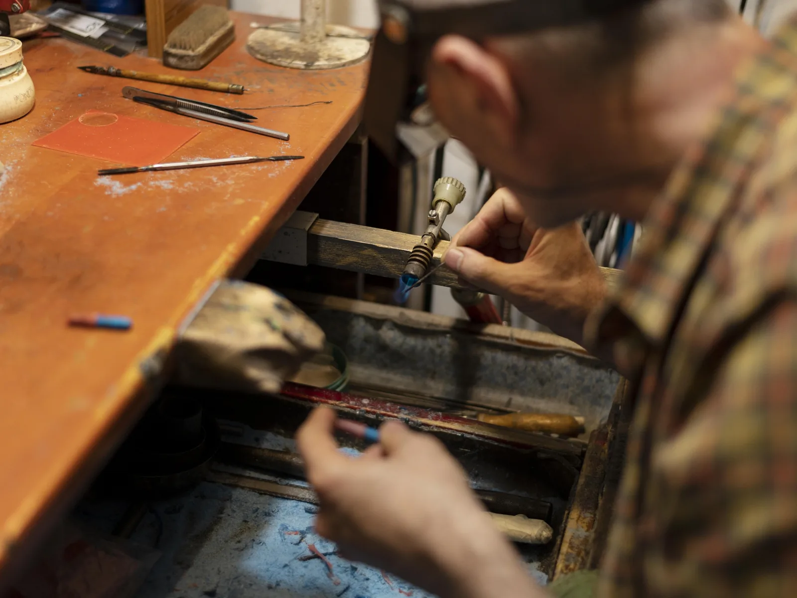 Two jewellers working at opposite sides of one long bench.